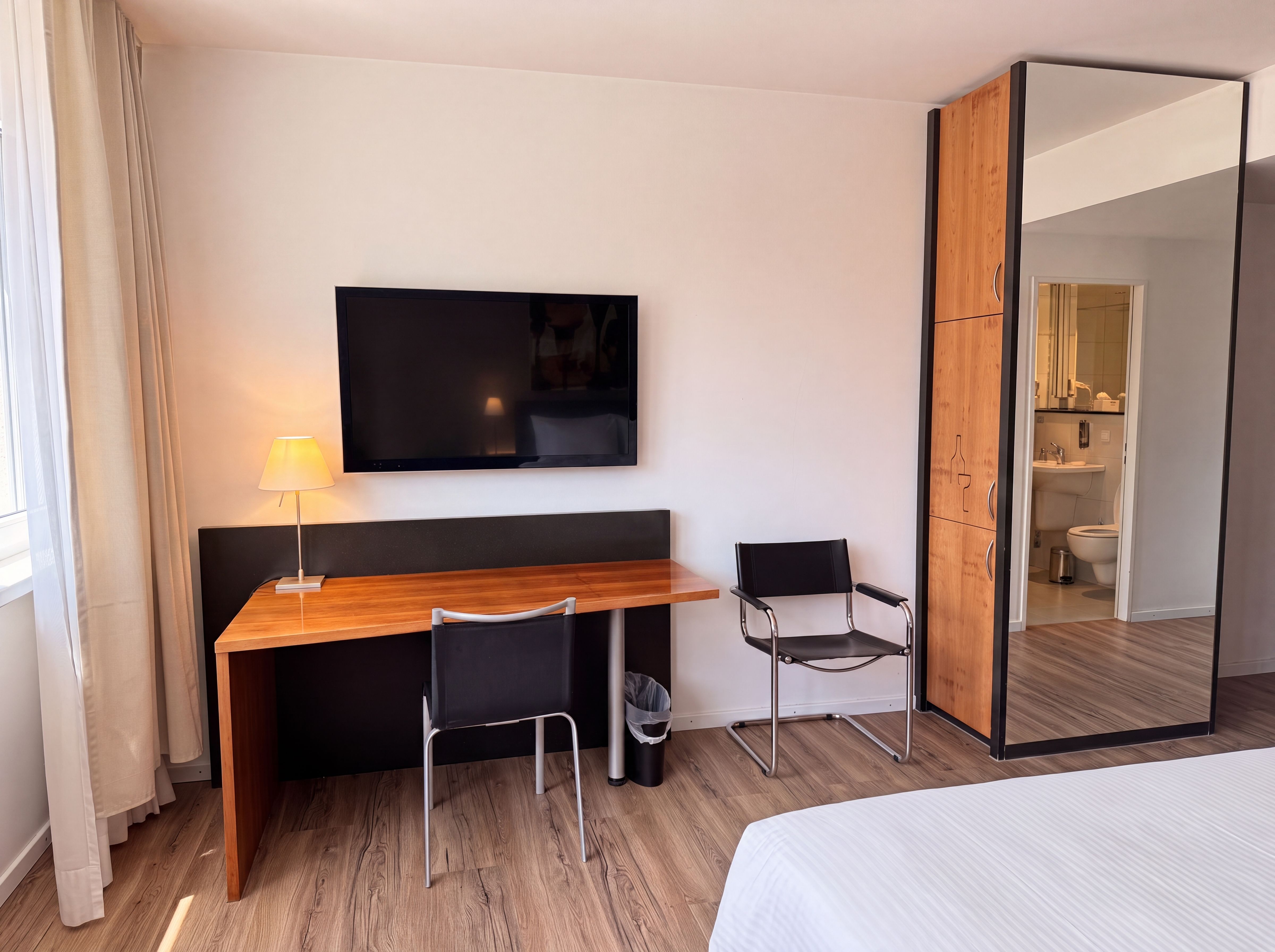 Zimmer mit Schreibtisch, Spiegelschrank und Blick ins Bad, Hotel Belair