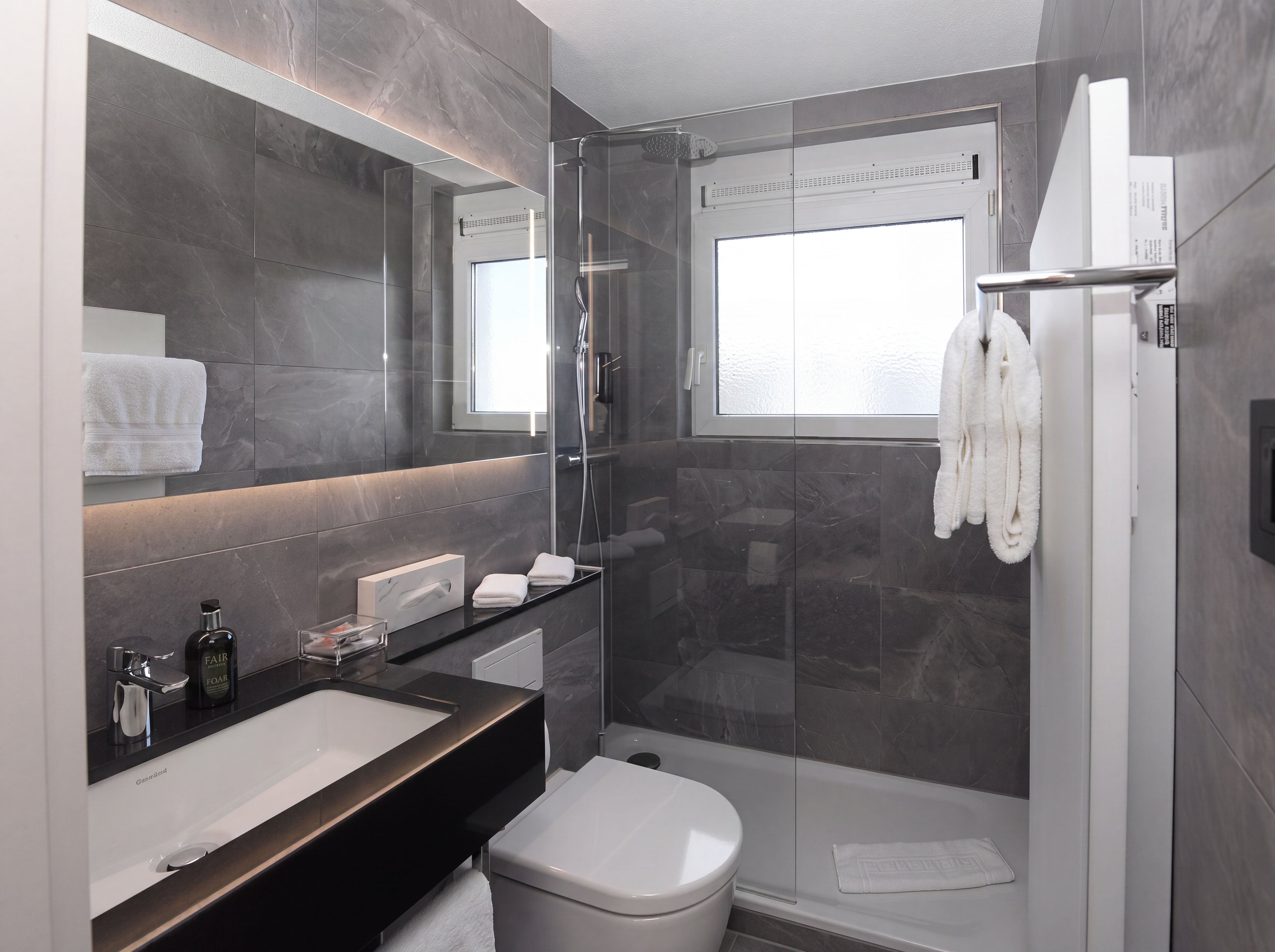 Badezimmer mit dunklen Steinfliesen und schwarzem Waschtisch, Hotel Belair