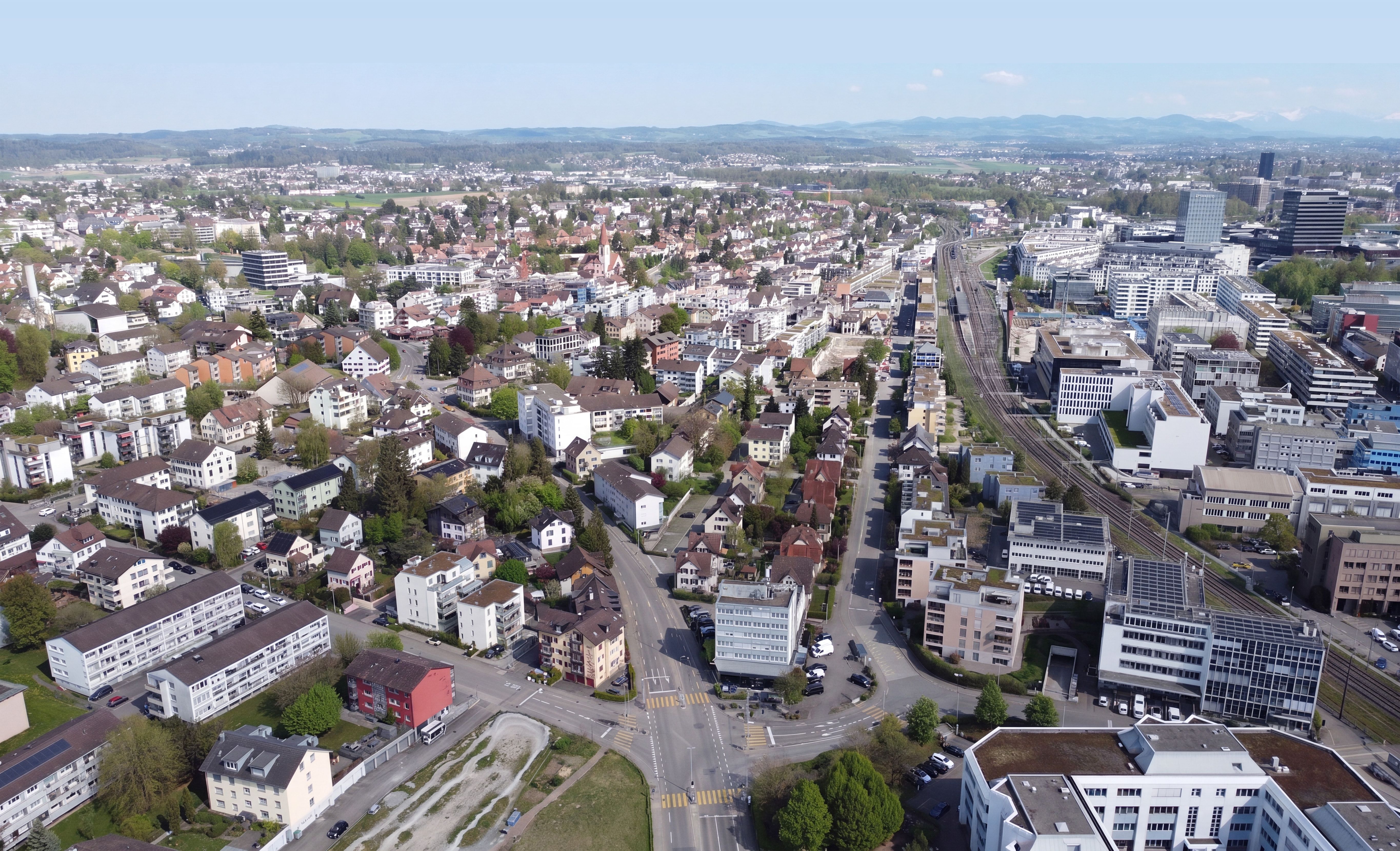 Weite Luftaufnahme von Wallisellen mit Bahnhof und Blick Richtung Zürich